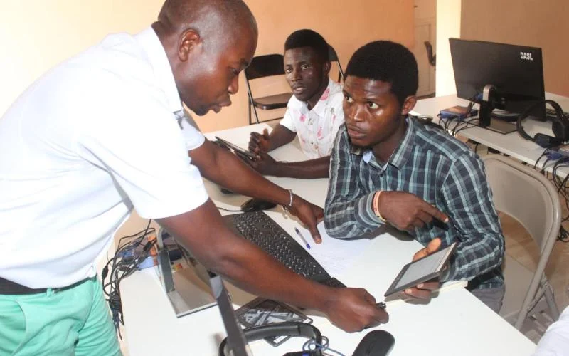 African students engage in learning within a classroom, emphasizing skill development crucial for localized digital ecosystems. This collaborative environment supports technological growth.